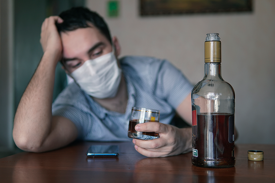 Study Reveals Insights on Pandemic-related Drinking & Mental Health; Stock image of man drinking whiskey slumped over table