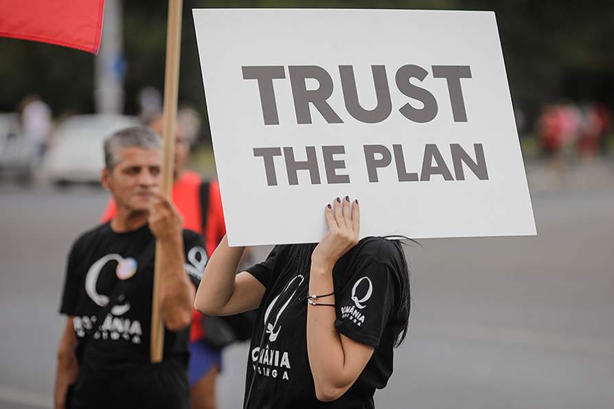 Study Explores How QAnon Went From Fringe to Mainstream on Twitter; Photo of pro-Trump protester holding up a sign that says "Trust the plan"