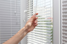 A person closing window blinds