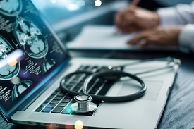 A sthethescope resting on a laptop open with medial imagery
