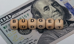 Wooden blocks spell out budget atop a $100 bill