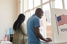 Two African American individuals casting ballots