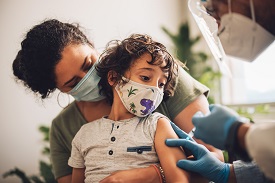 A child held by a woman gets a vaccine shot
