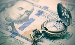 Timepiece over hundred dollar bills