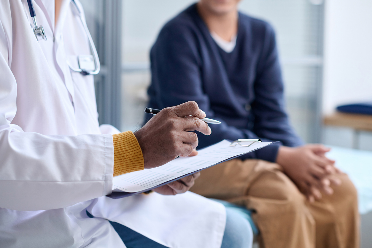 Doctor with clipboard consulting patient sitting on a table. 