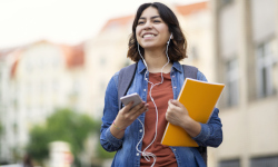 college student walking with a notebook and phone in hand