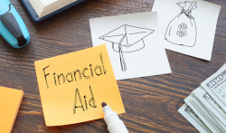 A post-it note on a desk with the words Financial Aid