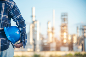 Man holding a hard hat with a city skyline behind him
