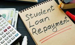 A yello pad with the words Student Loan Repayment written in black marker