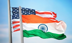 Flags of India and the United States waving against a blue sky