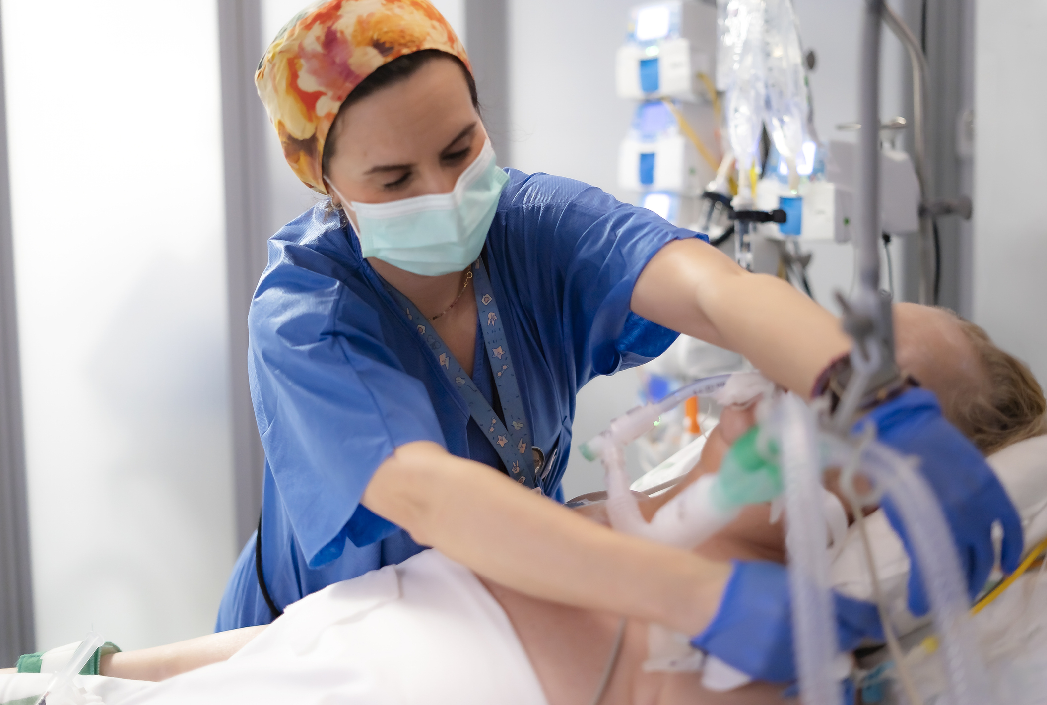 Nurse adjusting ventilator of patient. 