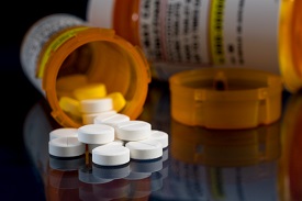 open pill bottle with pill strewn over surface