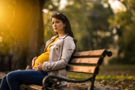 A pregnant woman sitting on a park bench
