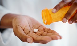 A person holding a tablet and a pill bottle in their hands