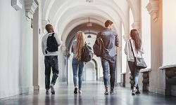 a group of college students walks down a hallway