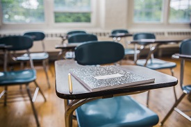 Notebook laying on an epmty classroom desk