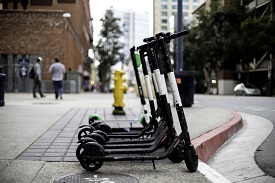 A row of e-scooters parked on a sidewalk