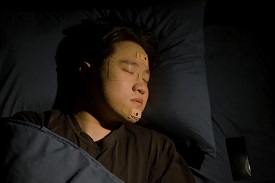 Man asleep with nodes attached to his face
