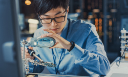 Someone using a magnifying glass to work on robotics