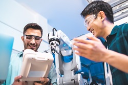 Two students test robotic arm