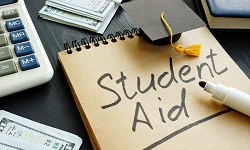 Student aid sign with small graduation cap and money