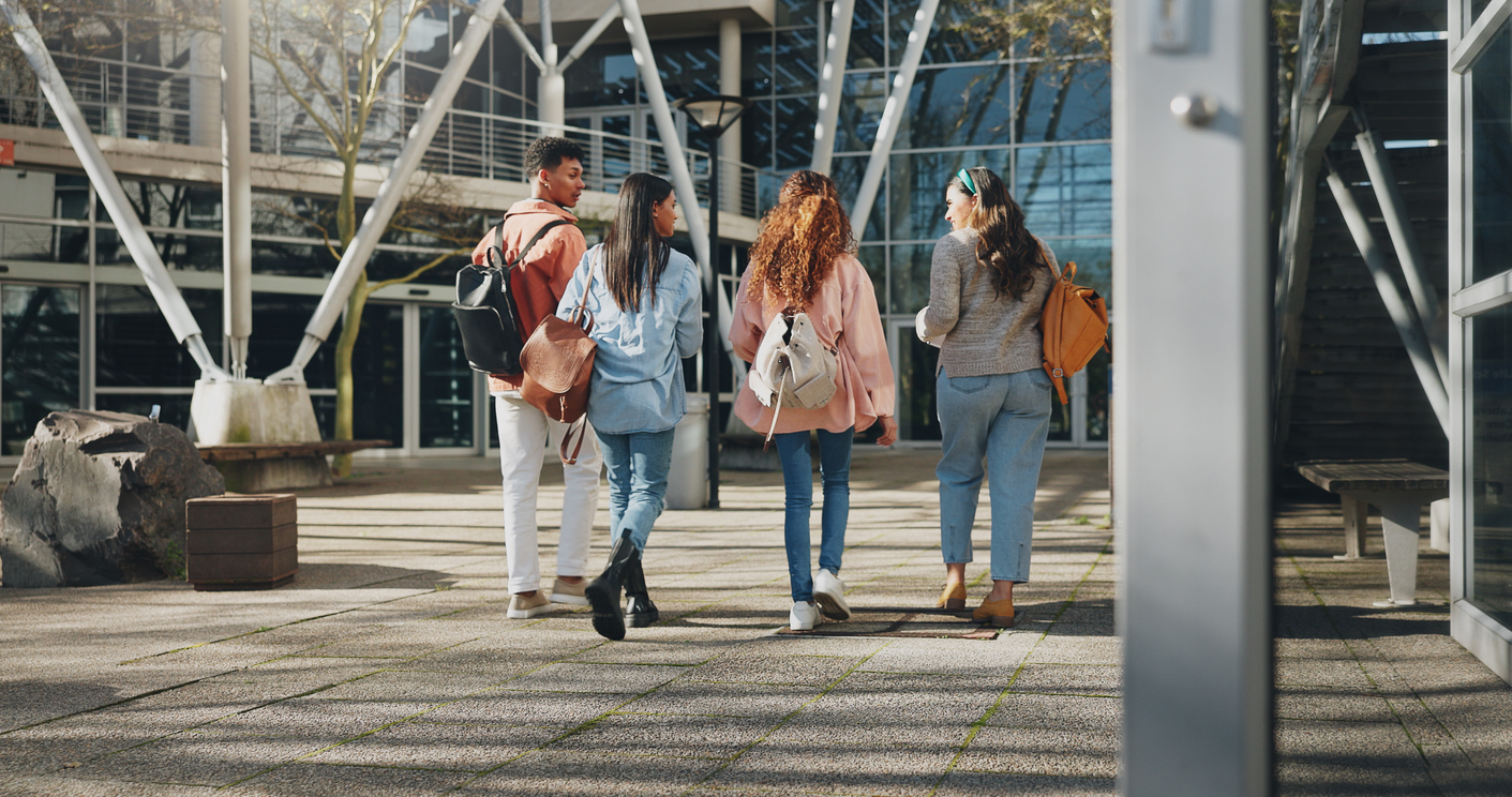 A group of four students walking on a modern campus