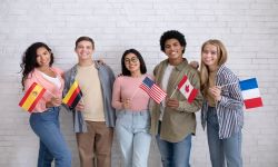 Five college-aged students holding up different country flags.