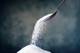 Sugar falling out of a spoon on a heap
