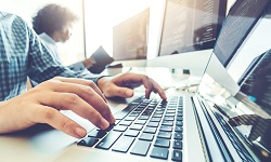 Close up of an individual's hands on a laptop keyboard