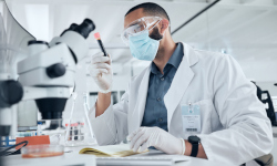 Researcher in a lab coat using a microscope