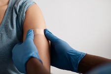 A person applies a bandaid to an arm