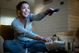 someone happy watching tv using the remote control