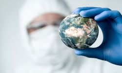 Person in protective clothing and gloves holding a small earth