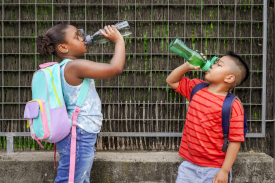 young children with backpacks drinking water from a bottle