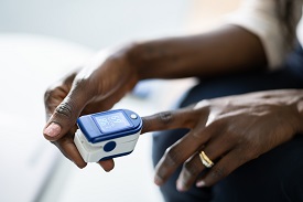 a person with a darker skin color using a pulse oximeter