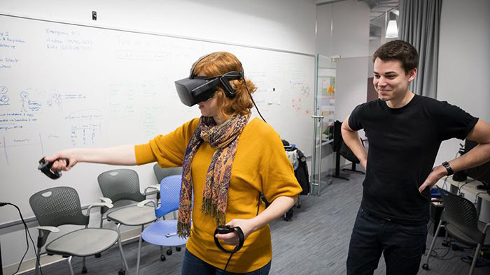 Jack Madden watches as Andrea Stevenson Won uses a virtual reality simulator.