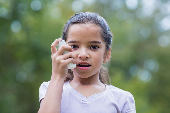 Young girl using inhaler