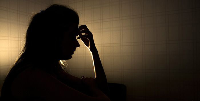 Image of young woman holding hand to forehead.