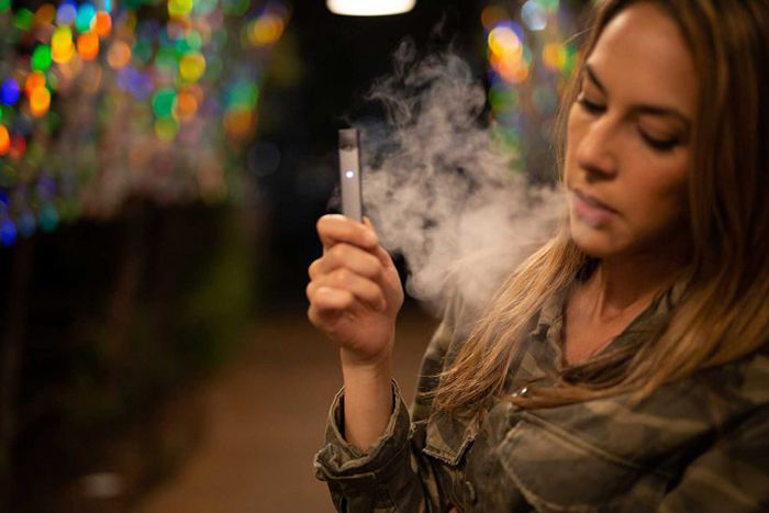 Image of a young woman smoking an e-cigarette.
