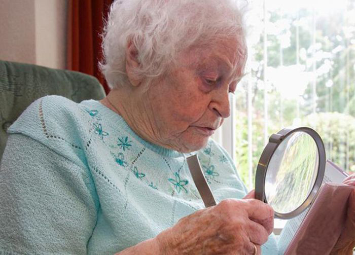 Image: Older woman using magnifying glass to read