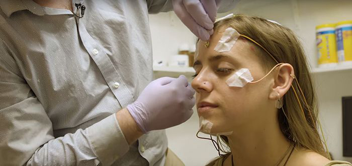 Researcher prepares undergraduate for sleep test