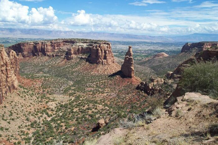 Towers and mesas of brown rock loom over the desert at Colorado National Monument. 
