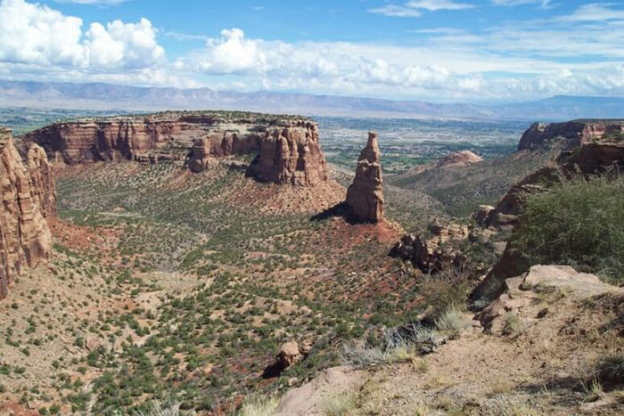 Towers and mesas of brown rock loom over the desert at Colorado National Monument.