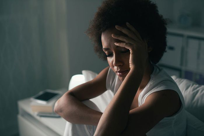 Image: woman with hand to forehead.
