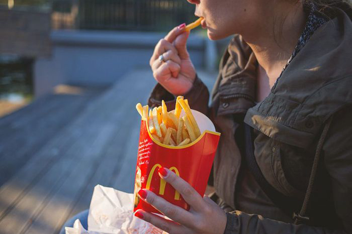 Image: young woman eating fast food