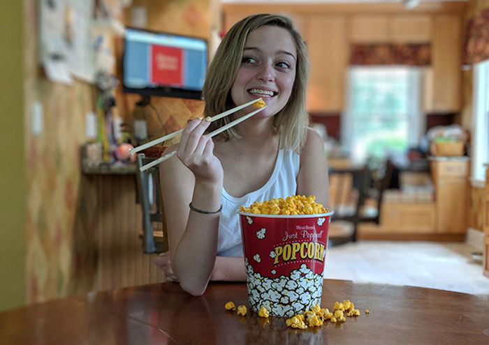 Woman eating popcorn with chopsticks