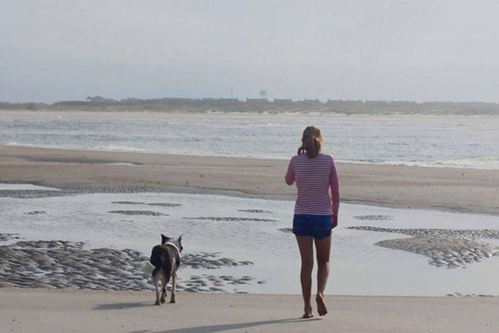 Woman walking dog on beach