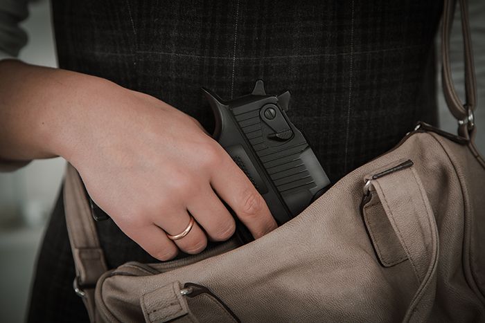 Woman pulling gun from purse