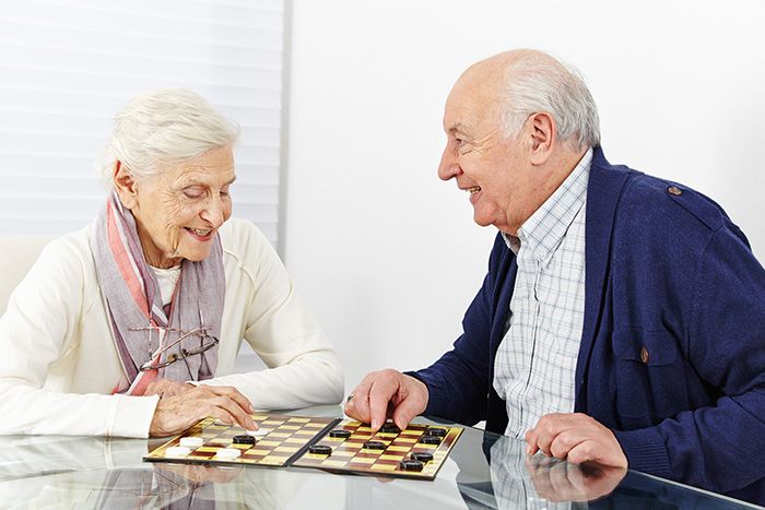 Elderly man and woman playing checkers