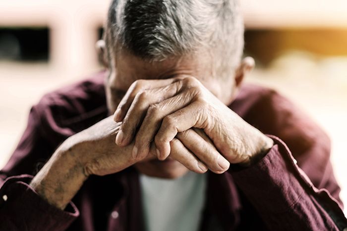 Senior with head in hands